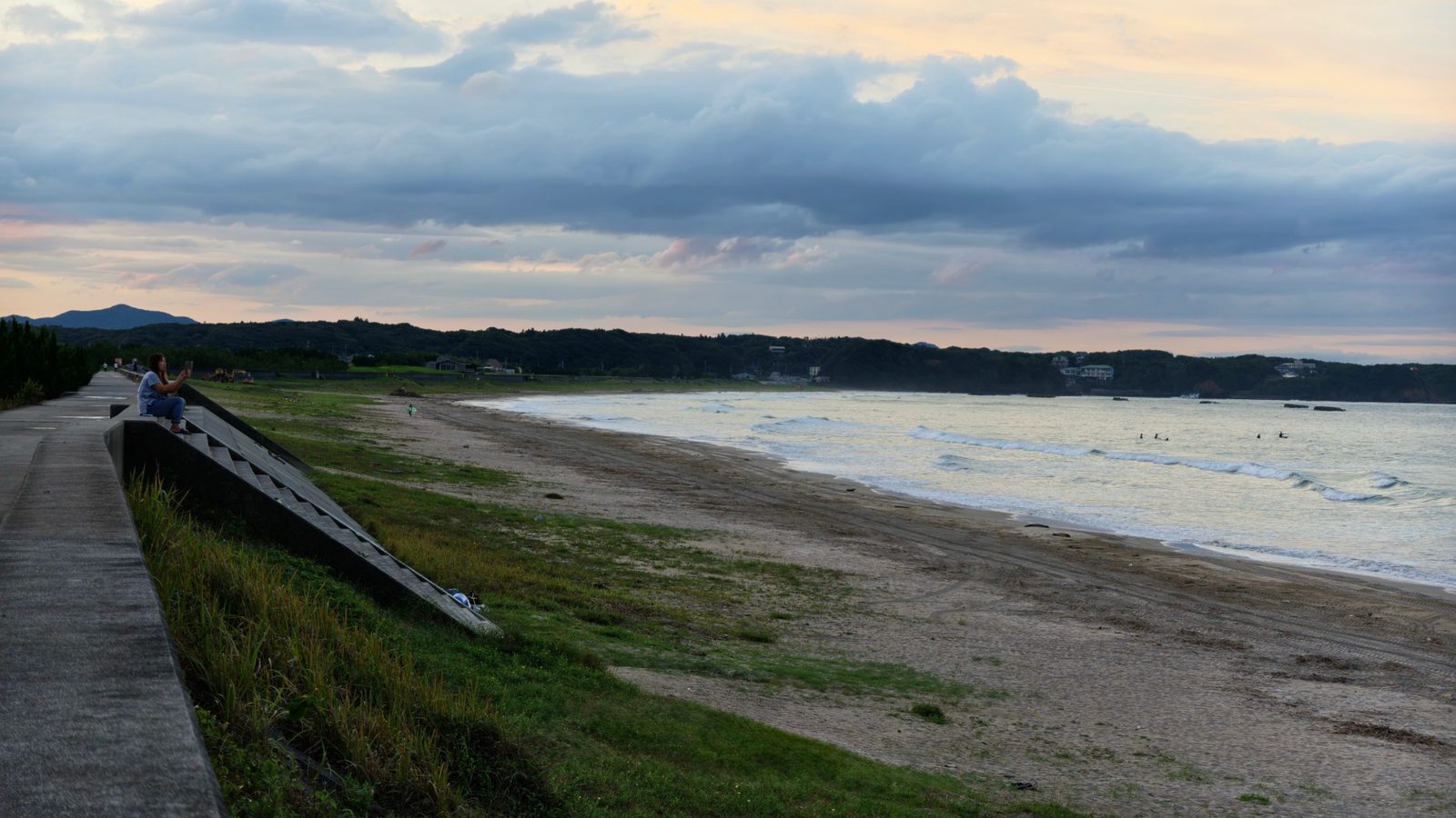 Surfers in the water off a long Ise-Shima beach at dusk